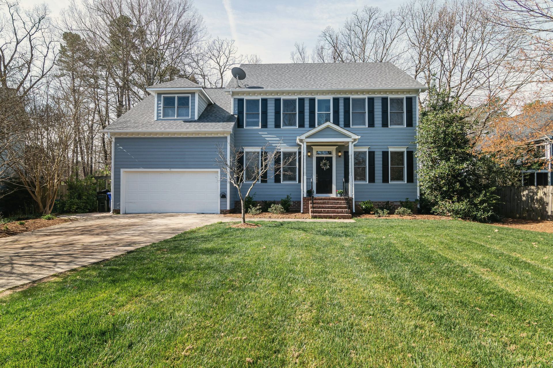 A two-story house behind a freshly striped front lawn